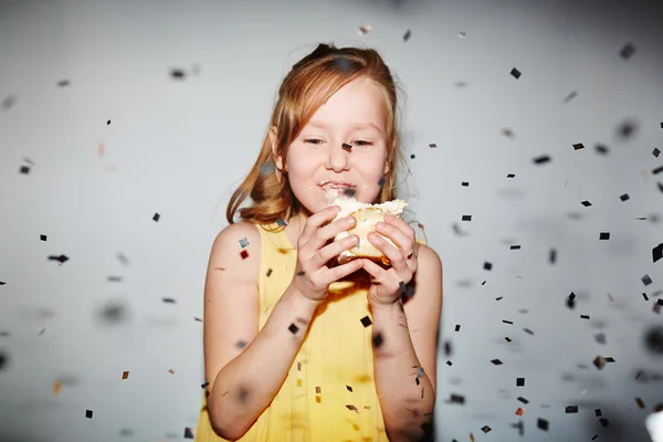 Menina comer bolo sob chuva confete — Fotografia de Stock