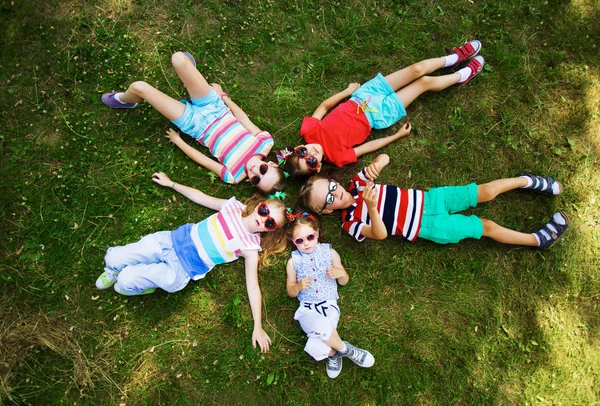 Vriendelijke kinderen ontspannen op groen gras — Stockfoto