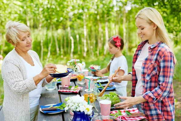 Kvinnor förbereder mat och servering bordet — Stockfoto