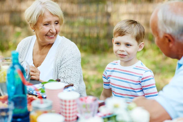 Jongen en grootouders zitten bij de tafel — Stockfoto