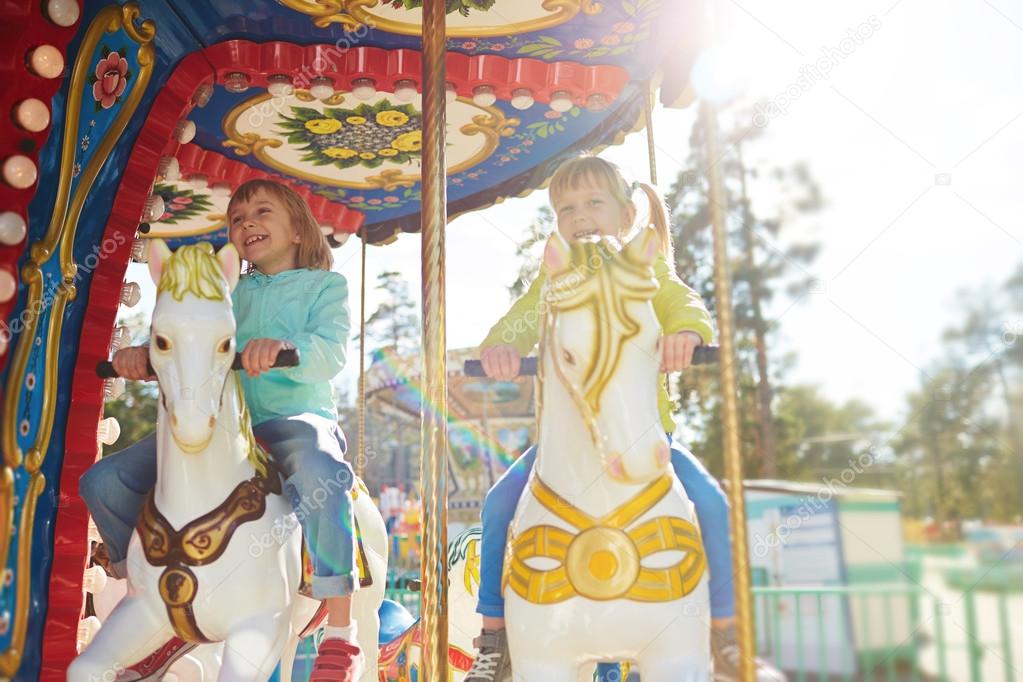Girls riding horses in amusement park 