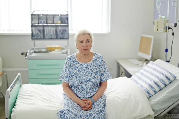 Femme âgée assise sur un lit d'hôpital — Photo