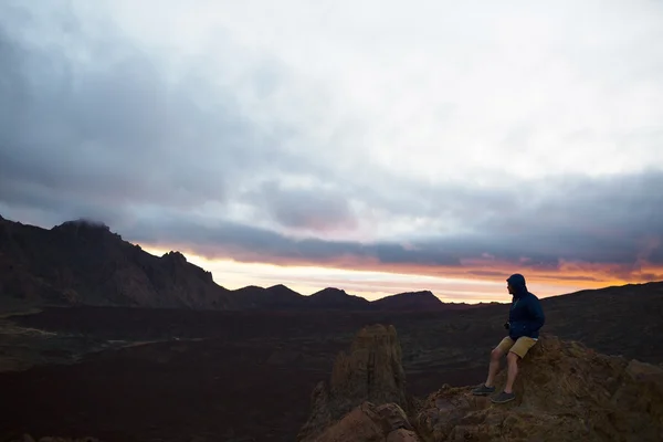 Young man sitting on peak of hill — Stock Photo, Image