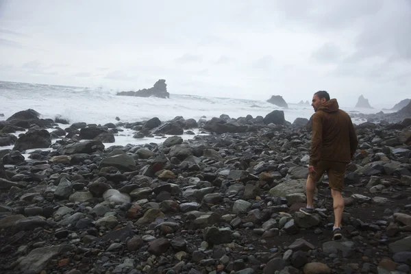 Hombre caminando por las piedras en el mar — Foto de Stock