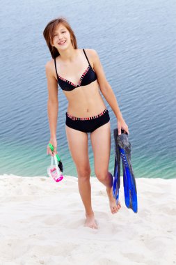 Girl in bikini carrying scubadiving equipment clipart