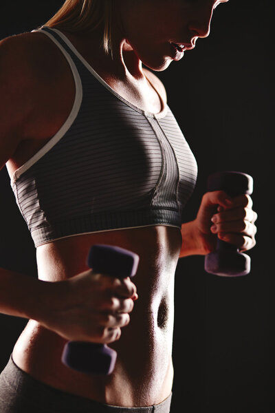 Женщина делает упражнения с гантелями

