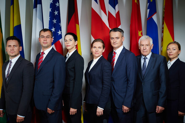 Ряд делегатов, смотрящих в камеру
