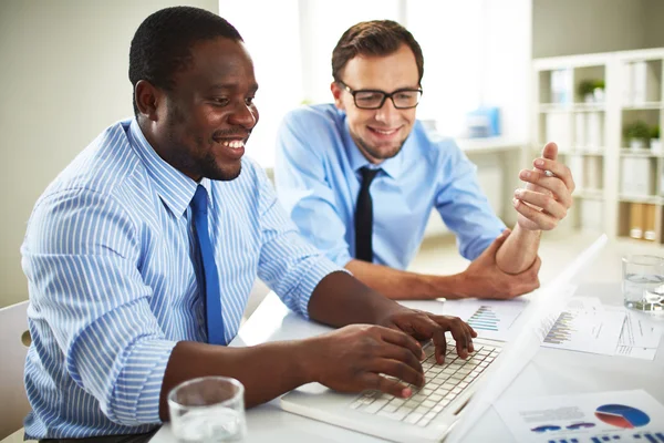 Skrattande affärsmän som arbetar med laptop på kontoret — Stockfoto