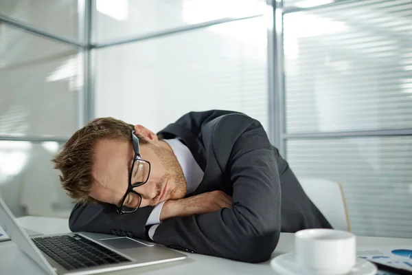 Уставший бизнесмен спит на рабочем месте — стоковое фото