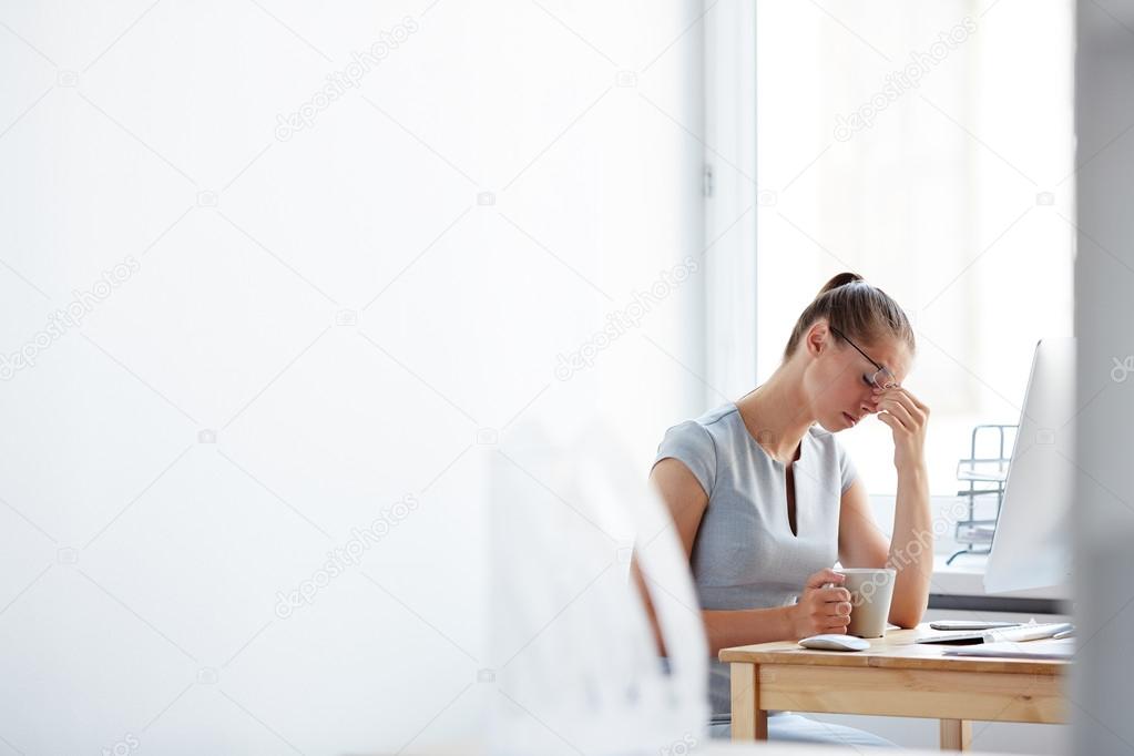 Tired woman sitting at computer desk 