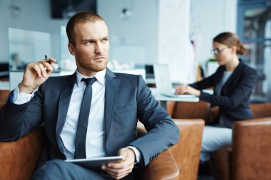 Dalgın bakmak ile oturan genç işadamı 