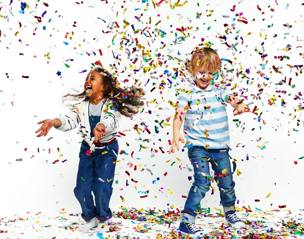 Niño y niña bailando bajo la lluvia de confeti — Foto de Stock