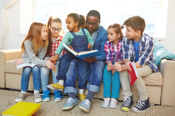 Uomo con bambini che legge un libro — Foto Stock