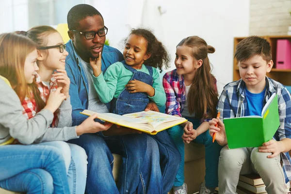 Niños en edad escolar leyendo con el profesor —  Fotos de Stock