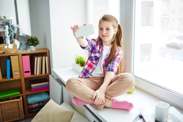 Schoolgirl taking selfie with smartphone — Stock Photo, Image