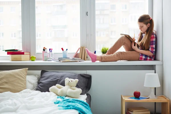 Thoughtful schoolgirl sitting on windowsill — Stock Photo, Image