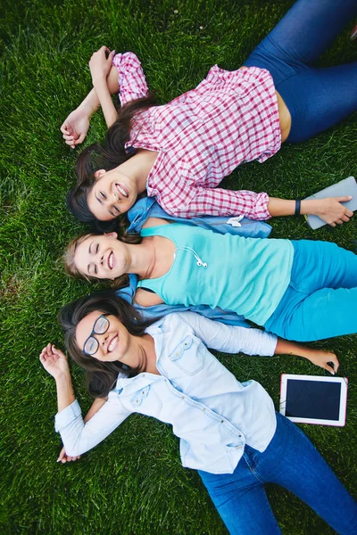 Estudantes felizes deitado na grama verde — Fotografia de Stock