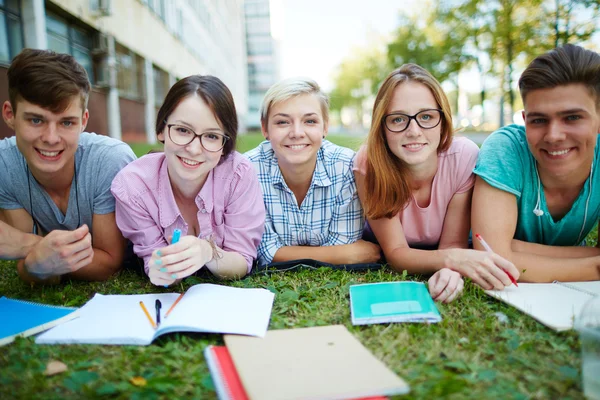 Högskolestudenter som liggande på gräset — Stockfoto