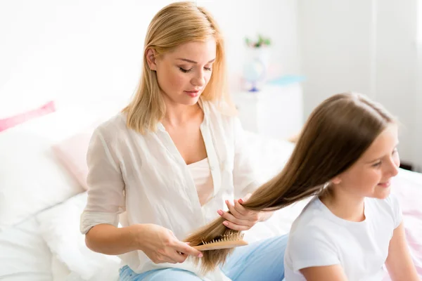 Mujer cepillando el pelo largo de hija — Foto de Stock