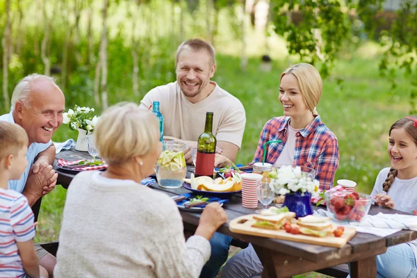 Happy family sitting by dinner table — Stock Photo, Image