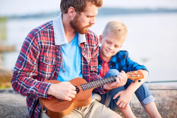 Man die zijn zoon te zien hoe ukulele spelen — Stockfoto