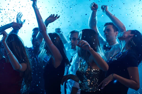 Ecstatic friends dancing in confetti — Stock Photo, Image