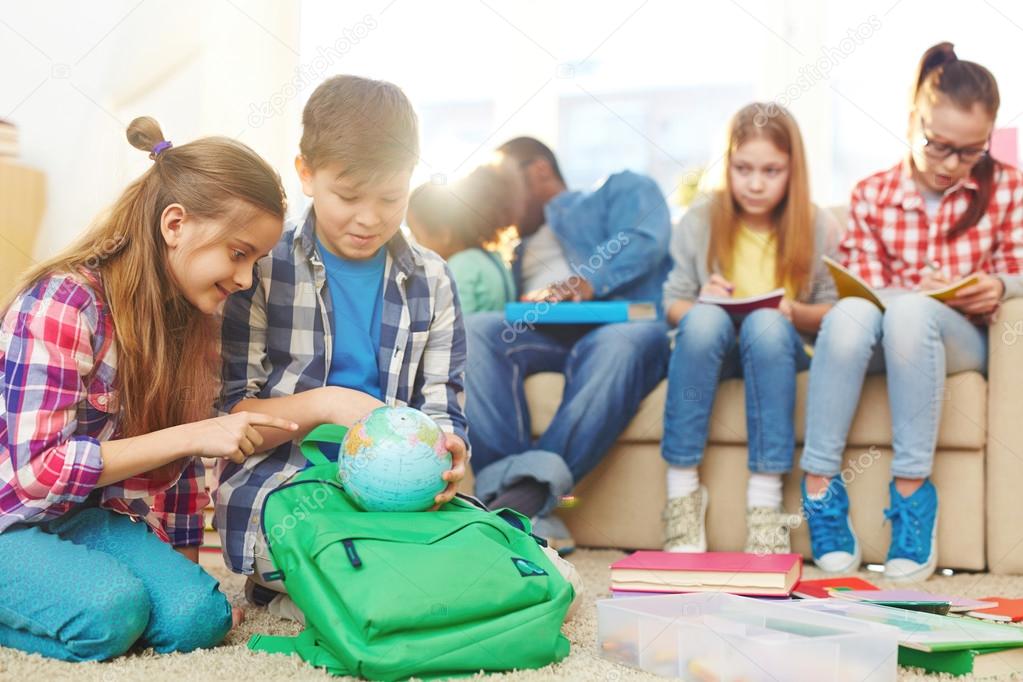 School children studying the globe 