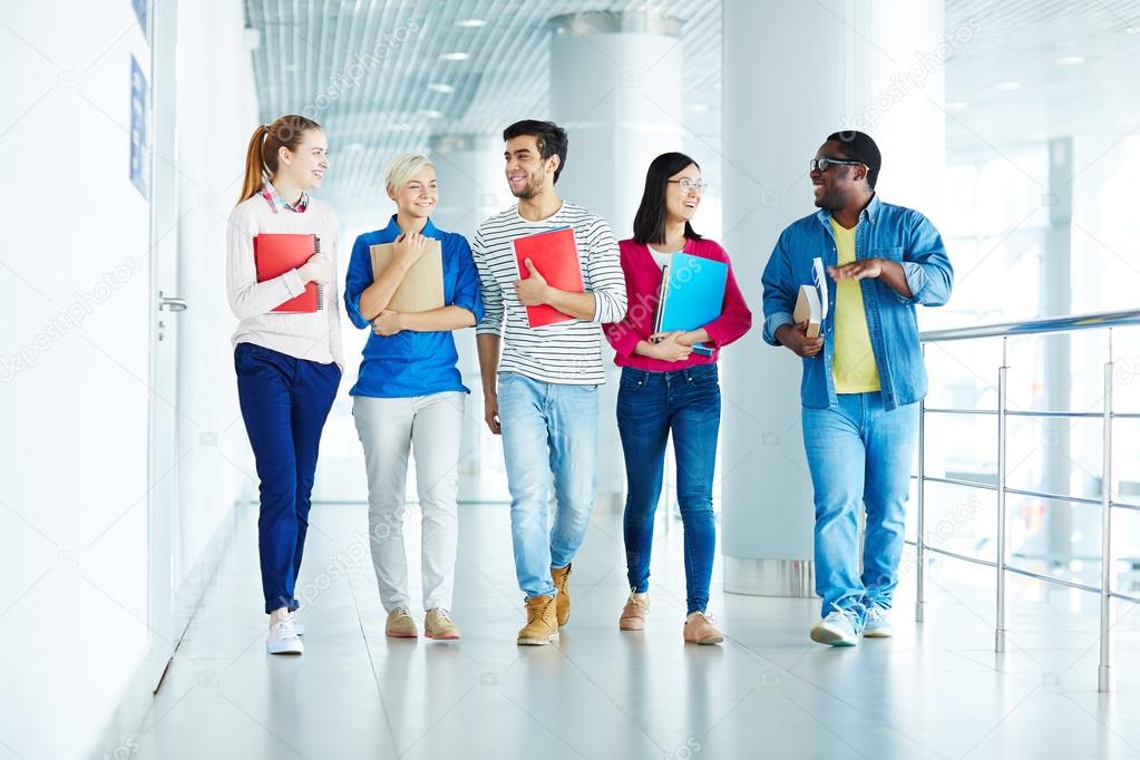 Group of intercultural students walking down corridor after classes