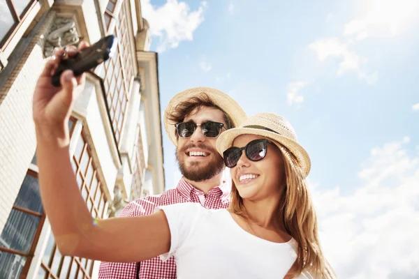 Pareja tomando selfie contra el cielo azul — Foto de Stock