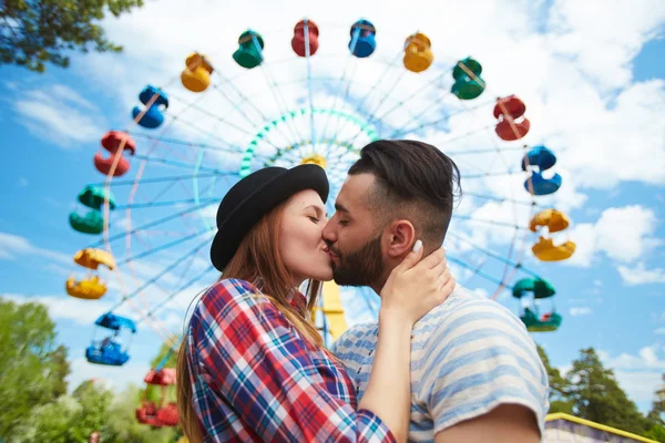 Couple kissing in front of Ferris wheel — Stock Photo, Image