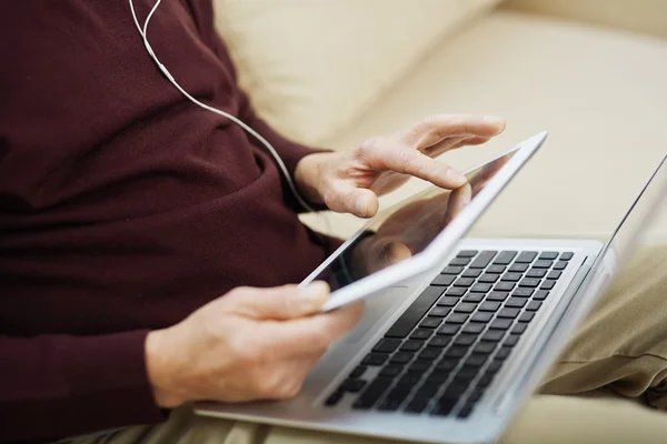 Äldre man sitter på soffan och använder sin laptop — Stockfoto