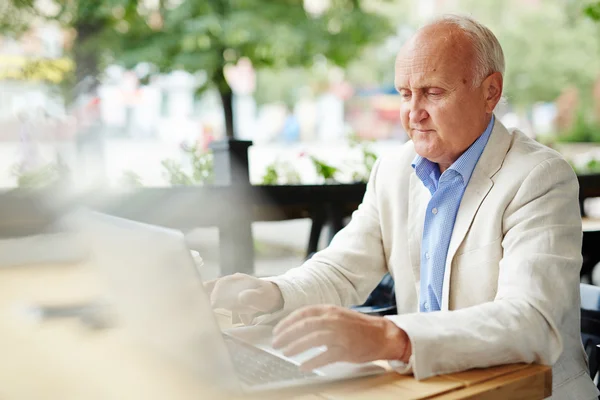 Senior-Blogger tippt auf Laptop — Stockfoto
