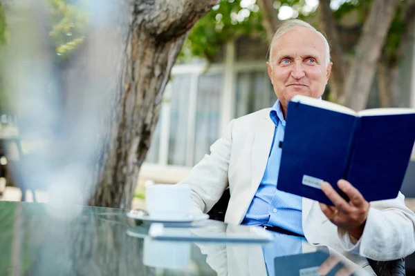 Senior sitzt mit Notizbuch — Stockfoto