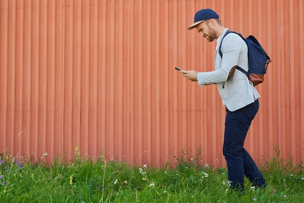 Hombre con smartphone moviéndose a lo largo de la pared — Foto de Stock