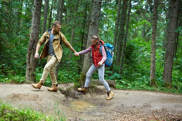 Hikers crossing puddle — Stock Photo, Image