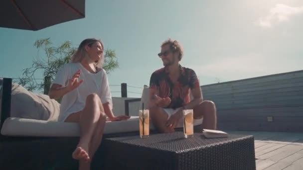 現代的なカップルのアークドリーアウトショットは 青空の下で屋外テラスでカクテルを飲みながらおしゃべり — ストック動画