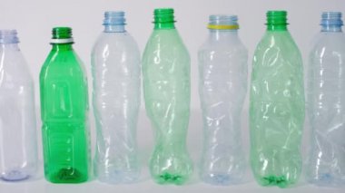 Boş plastik su şişeleri sırada duruyor ve izole edilmiş beyaz arka plana çarpıp düşüyor.