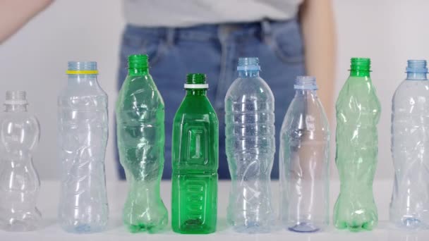 前排站着的空塑料瓶的中段特写和女性环保积极分子在白色背景下粉碎瓶子 — 图库视频影像