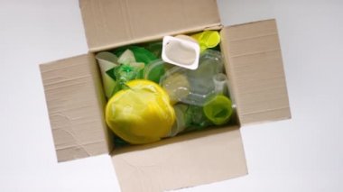 Kavramsal üst görünüm, insanların ekolojiye karşı dikkatsiz tutumlarını gösteren plastik eşyalarla dolu bir kutunun görüntüsü.