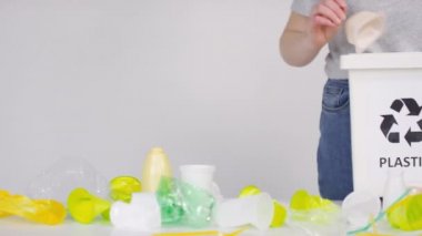 Beyaz arkaplanda geri dönüşüm sembolü olan plastiği konteynıra sıralayan kadın ekoloji aktivistinin orta bölüm görüntüleri