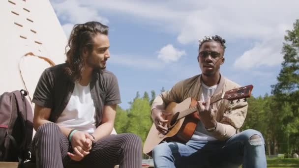两个多民族男性朋友在户外玩得开心 一边唱歌一边弹吉他的低角度中镜头 — 图库视频影像