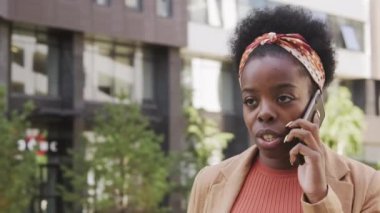  Sabah işe giderken cep telefonuyla konuşan ve kahve içen siyahi iş kadınının izini sürmek.