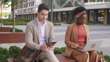  İş kadını ve işadamının tablet ve dizüstü bilgisayar kullanarak bankta oturması.