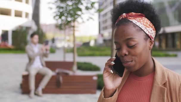 屋外で携帯電話で話して幸せなアフリカ系アメリカ人女性の追跡ショット — ストック動画