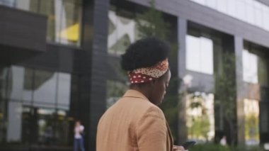  Dışarıda cep telefonuyla dolaşan başarılı siyahi iş kadınlarının yavaş yavaş izini sürüyorum.