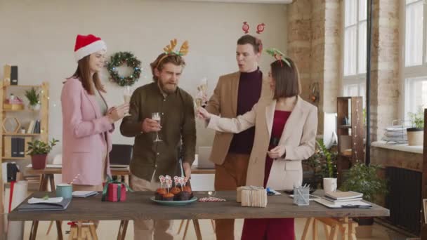 在庆祝圣诞的同时 戴着喜庆的头巾 戴着圣诞礼帽的同事们一边喝着香槟一边拍了照 — 图库视频影像