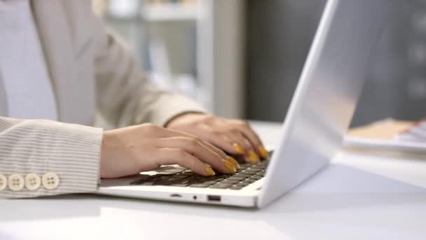 明亮而现代的教室里 用黄色指甲油在笔记本电脑上打字的无法辨认的女性手的衣服 — 图库视频影像