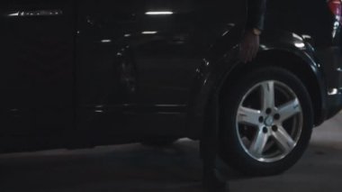 Güneş gözlüklü, vahşi sakallı bir adamın yeraltı otoparkında inerken çekilmiş görüntüleri.