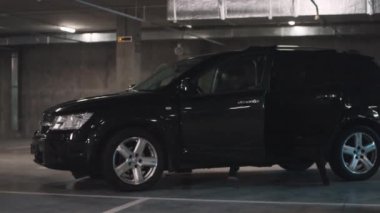 Siyah deri ceketli üç çok ırklı suçlunun karanlık yeraltı otoparkında cipten inerken çekilmiş fotoğrafları.