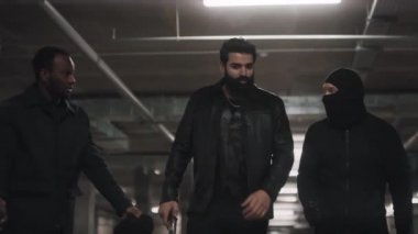 Arap, Afro-Amerikan ve Kafkasyalı gangsterlerin kameraya doğru yürürken yüzlerindeki kar maskelerini çıkarırken ve etrafta polis ararken suç duyurusu yaptığına yemin ederken orta boy bir fotoğraf.